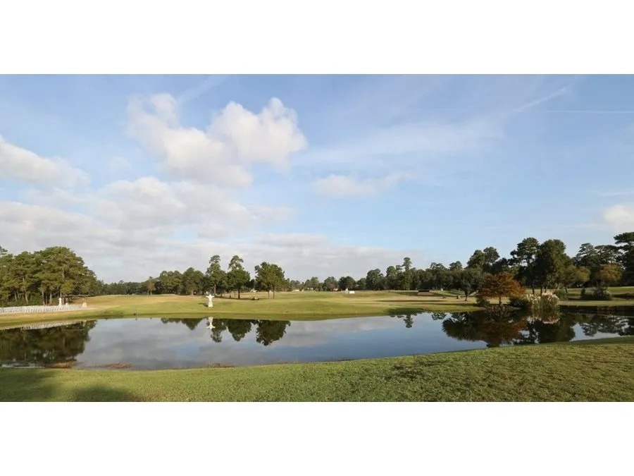 Sky, clouds, and course features reflected in the water of the lake.