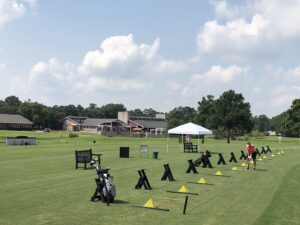View of the driving range featuring a row of stands and accompanying pyramids of golf balls, ready to hit.